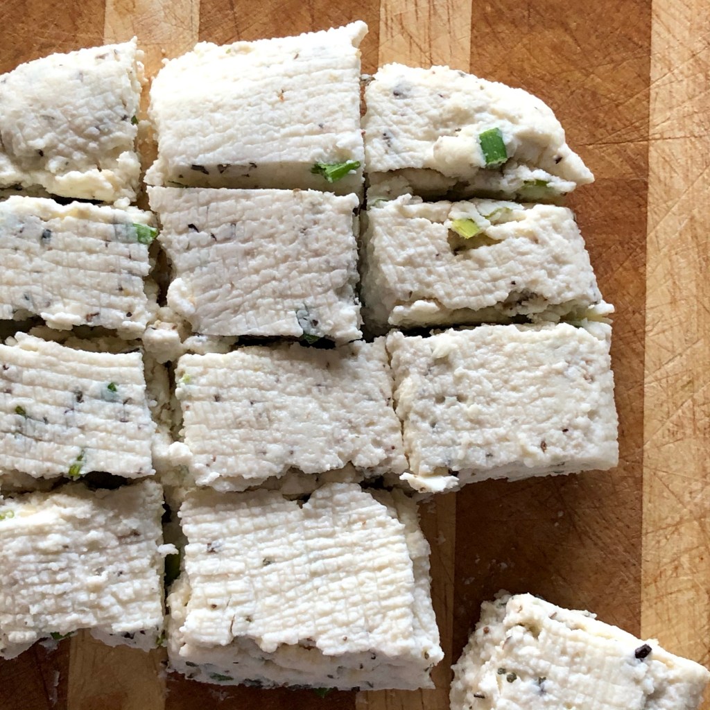 Garlic Herb Paneer, placed on a wooden cutting board and cut into cubes